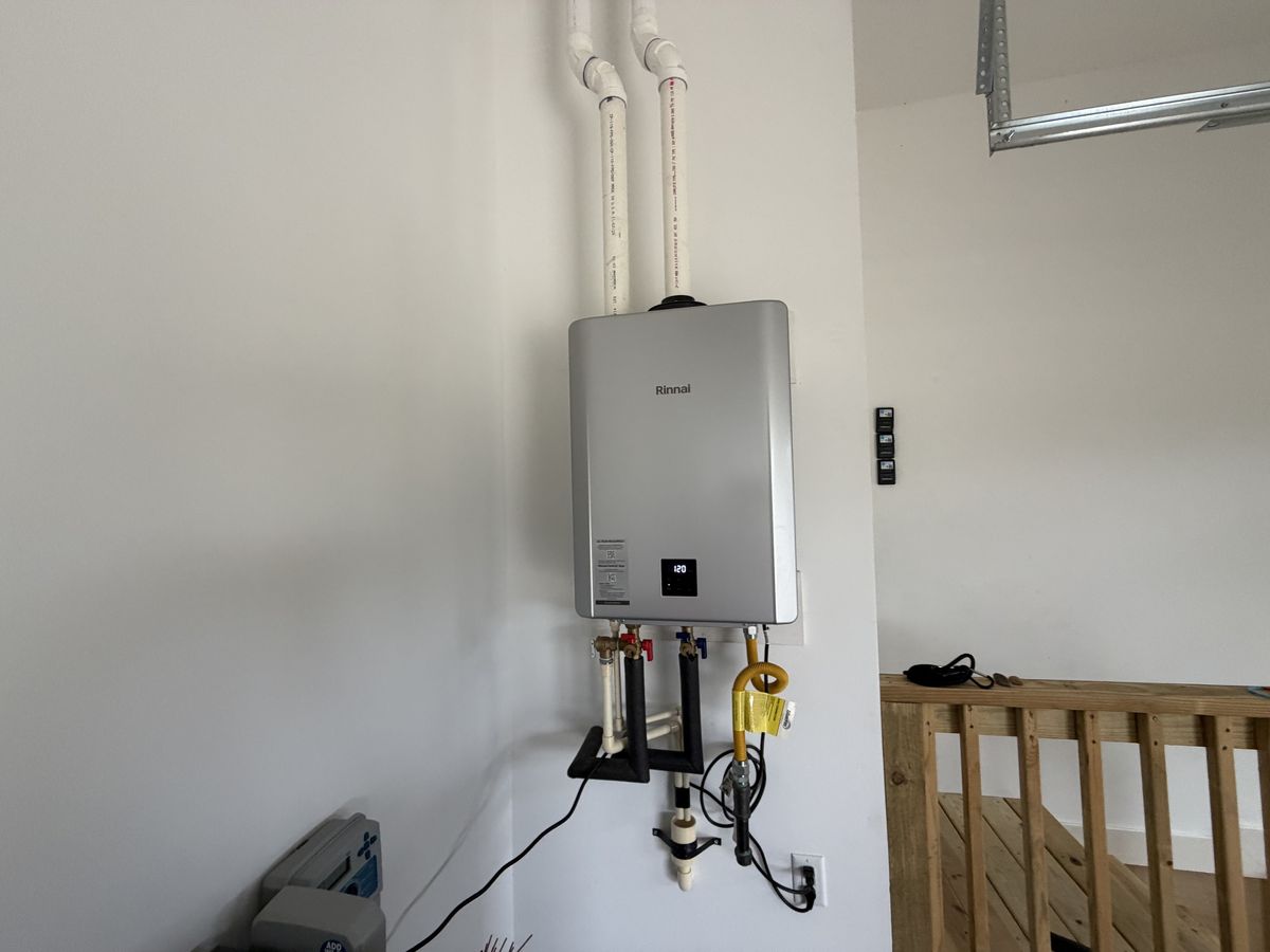 A condensing tankless unit with two plastic vent pipes running up the wall