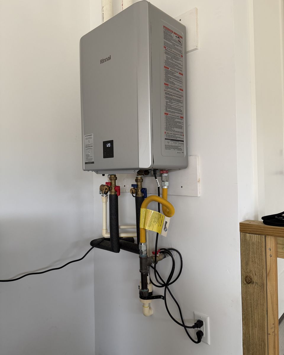 A newer condensing tankless water heater on a white garage wall