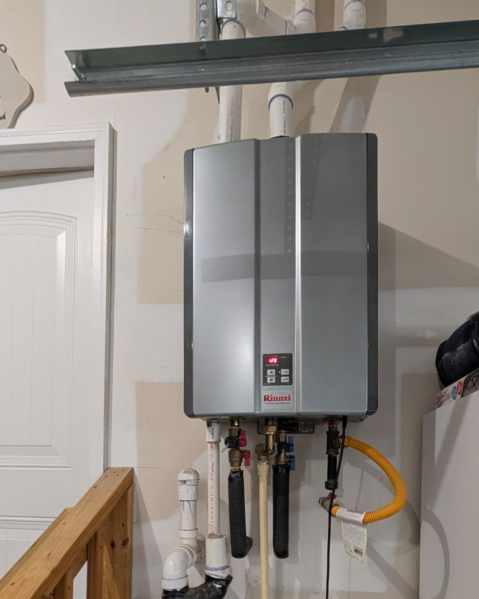 A wall-mounted condensing tankless water heater in a garage beside the door into the house