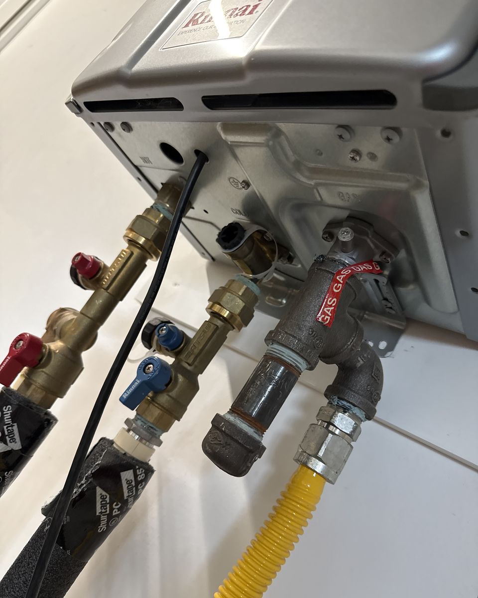 Close-up of the gas connection with a capped drip leg and the water service valves