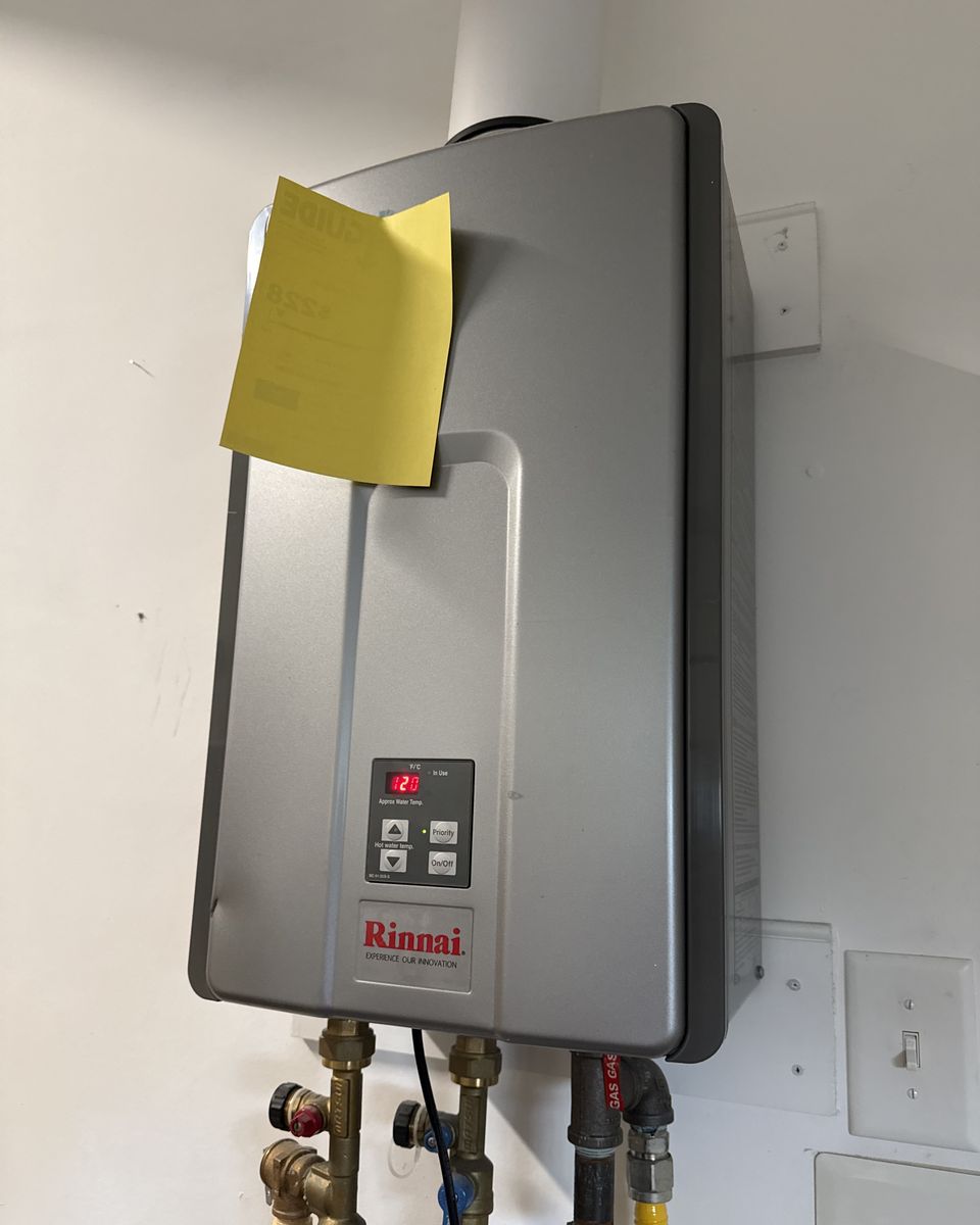 Front of a wall-mounted tankless water heater with its yellow EnergyGuide label
